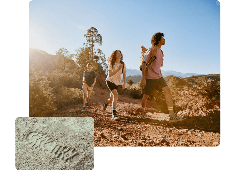 Three people hike a sunny mountain trail; inset shows a close-up of a shoe print in sandy soil.