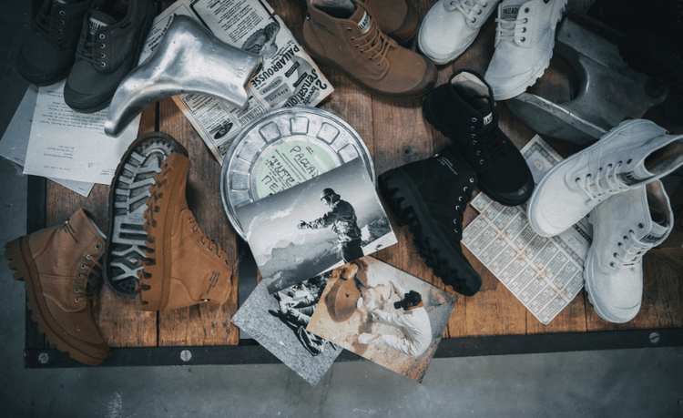 Wooden table with boots, vintage photos, old newspaper, typewritten letters, and film reel canister.