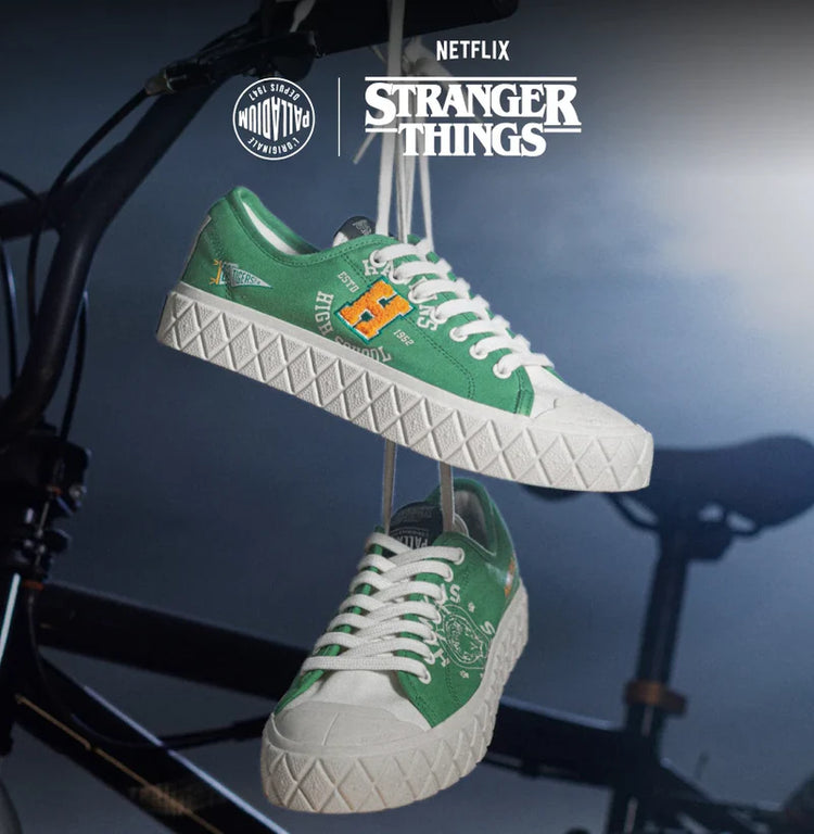 Green and white sneakers with Stranger Things branding hanging on a bike frame.