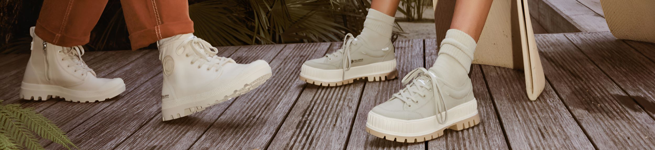 Image of people wearing the Pampa Hi Zip Organic and Pallashock Lo Organic on a wooden deck with green leaves